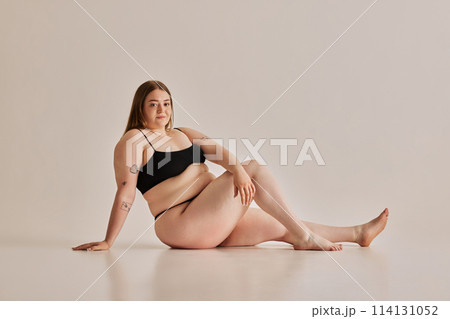 Strength of beauty. Young woman comfortable in her own skin, promoting positive body image against grey studio background Strength of beauty. Young woman comfortable in her own skin, promoting positive body image against grey studio background 114131052