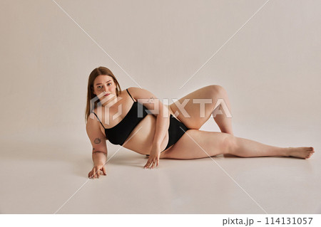 Strength of beauty. Young woman comfortable in her own skin, promoting positive body image against grey studio background 114131057