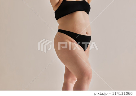 Beauty and uniqueness of natural body shapes. Cropped image of oversized feme body in nerdwear against grey studio background 114131060