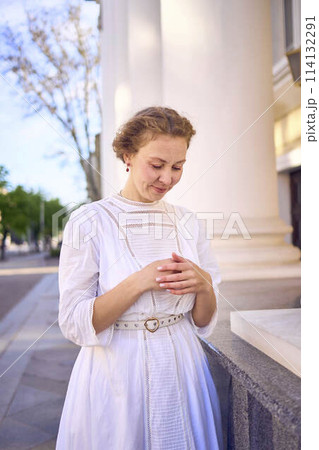 elegant middle age woman in white vintage dress near theater with antique colonnades elegant middle age woman in white vintage dress near theater with antique colonnades 114132291