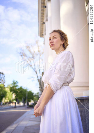 elegant middle age woman in white vintage dress near theater with antique colonnades elegant middle age woman in white vintage dress near theater with antique colonnades 114132294