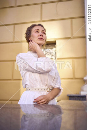 elegant middle age woman in white vintage dress near theater with antique colonnades elegant middle age woman in white vintage dress near theater with antique colonnades 114132356