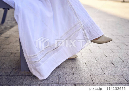 elegant middle age woman in a white vintage dress sitting on a bench in the morning city elegant middle age woman in a white vintage dress sitting on a bench in the morning city 114132653