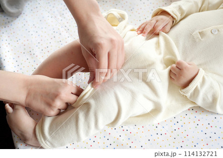 A mother dressing her little baby boy boy at home. childhood parenthood and growing up family concept real people 114132721