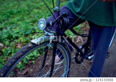 elderly woman walking in spring forest with bicycle and yoga mat 114133088