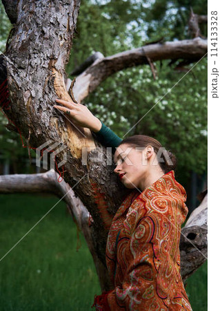 Slavic girl in a scarf with dead tree 114133328