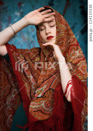 Slavic girl in a scarf on blue background Slavic girl in a scarf on blue background 114133336