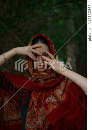 Slavic girl in a scarf pray in forest Slavic girl in a scarf pray in forest 114133346