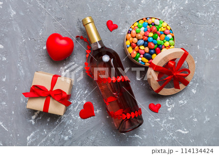 Bottle of red wine on colored background for Valentine Day with gift and chocolate. Heart shaped with gift box of chocolates top view with copy space Bottle of red wine on colored background for Valentine Day with gift and chocolate. Heart shaped with gift box of chocolates top view with copy space 114134424