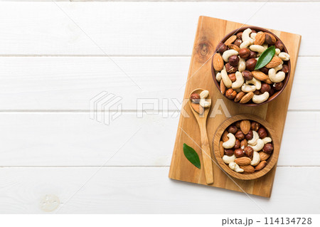 Assortment of nuts in wooden bowl on colored table. Cashew, hazelnuts, walnuts, almonds. Mix of nuts Top view with copy space 114134728