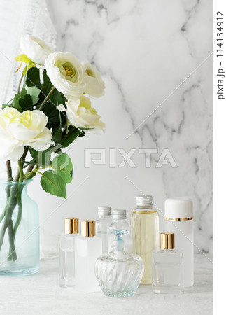 大理石を背景に並べた様々なタイプの化粧品容器と白い花 114134912
