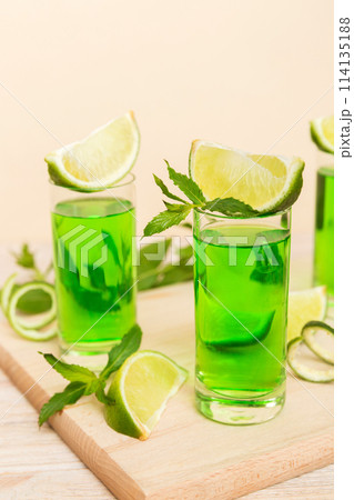Sweet refreshing mint liqueur, with ice and mint leaves on table background, Shots with lime slice and mint flat lay 114135188