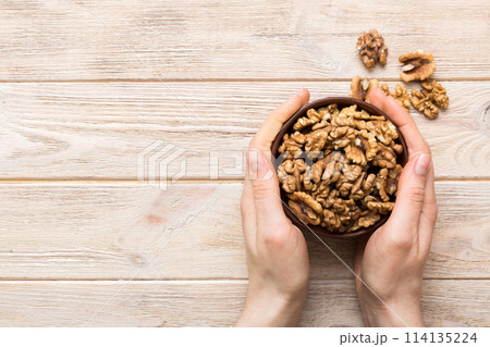 Woman hands holding a wooden bowl with walnut nuts. Healthy food and snack. Vegetarian snacks of different nuts 114135224
