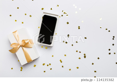 Opened gift box with gold ribbon and smartphone on color background, top view. Blank open box packaging mockup , Template for your design - branding mockup 114135382