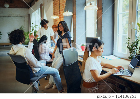 Productive coworking. Young people in modern office, maintaining productivity, working on gadgets. Positive ad comfort atmosphere Productive coworking. Young people in modern office, maintaining productivity, working on gadgets. Positive ad comfort atmosphere 114136253