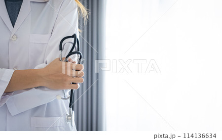 The female doctor held a stethoscope and stood in the ward with a folded arm 114136634