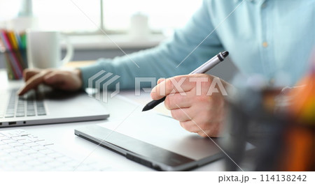 A young designer holds a pen from a tablet in his 114138242