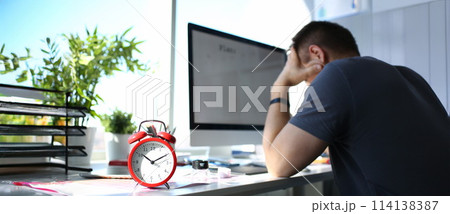 Red alarm clock stand at worktable with thoughtful man Red alarm clock stand at worktable with thoughtful man 114138387