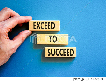 Exceed to succeed symbol. Concept words Exceed to succeed on beautiful wooden blocks. Beautiful blue table blue background. Businessman hand. Business and exceed to succeed concept. Copy space. 114138491