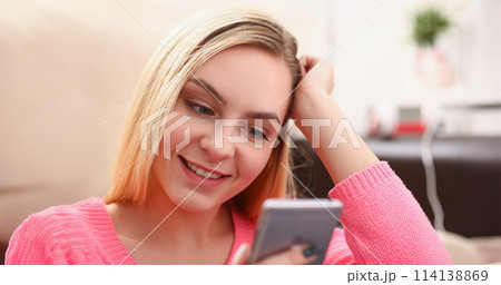 young pretty blond womansit on sofa hold smartphone in hands 114138869