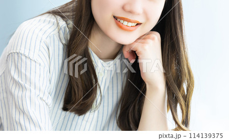 笑顔で頬杖をつく若い女性 114139375