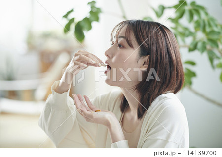 ベッドでサプリを飲む20代女性 114139700