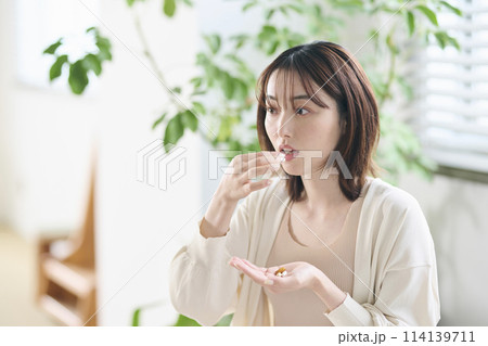 ベッドでサプリを飲む20代女性 114139711