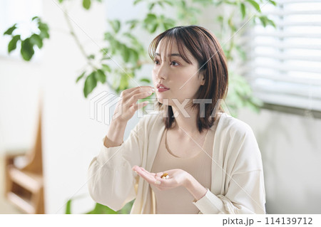 ベッドでサプリを飲む20代女性 ベッドでサプリを飲む20代女性 114139712
