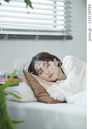 ベッドで眠る20代女性 ベッドで眠る20代女性 114139784