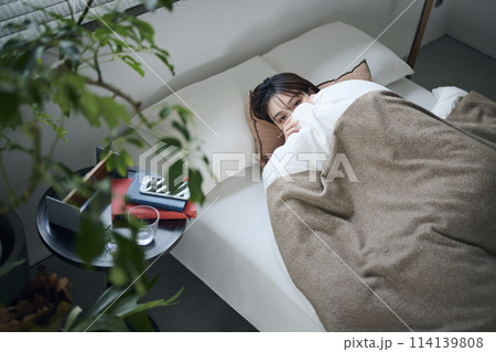ベッドで横になる20代女性 114139808