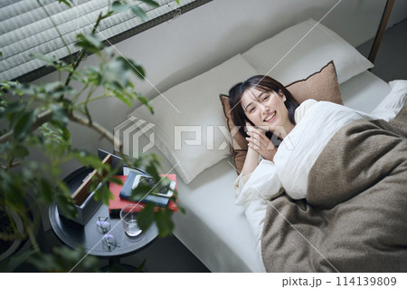 ベッドで横になる20代女性 114139809