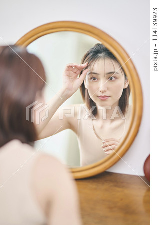 鏡の前でヘアセットをする20代女性 114139923