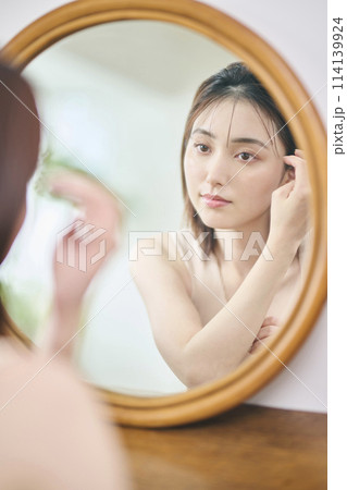 鏡の前でヘアセットをする20代女性 鏡の前でヘアセットをする20代女性 114139924