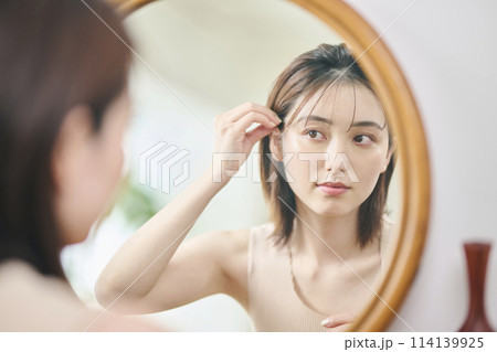 鏡の前でヘアセットをする20代女性 鏡の前でヘアセットをする20代女性 114139925