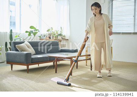 リビングで掃除機をかける20代女性 114139941
