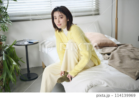 ベッドの上で靴下を履こうとする20代女性 ベッドの上で靴下を履こうとする20代女性 114139969