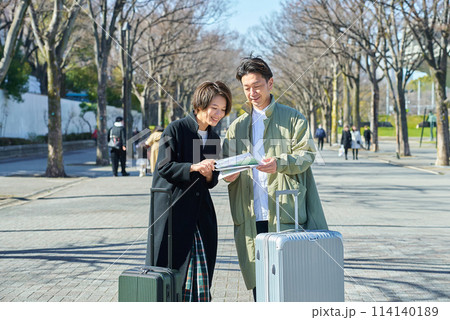 スーツケースを持って道に迷う男女 114140189