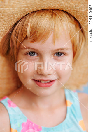 A young girl is smiling and wearing a straw hat A young girl is smiling and wearing a straw hat 114140468