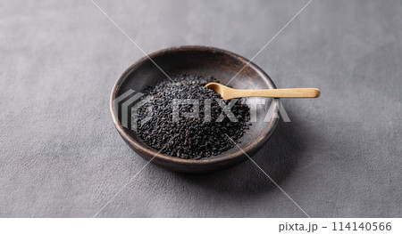 Black sesame seeds in a wooden bowl on a dark background. 114140566