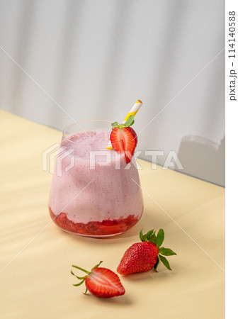 A strawberry milkshake or smoothie in glass with strawberries on a yellow background A strawberry milkshake or smoothie in glass with strawberries on a yellow background 114140588