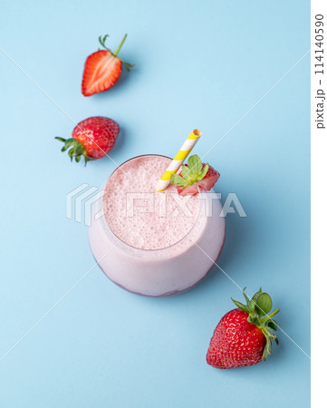 A strawberry milkshake or smoothie in glass with berry on a blue background 114140590