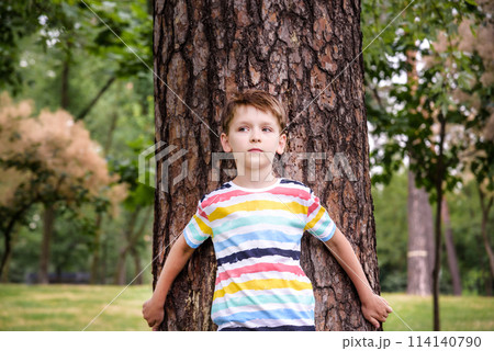 Little boy hugs a tree trunk - children love the nature, sustainability concept. Save the nature 114140790