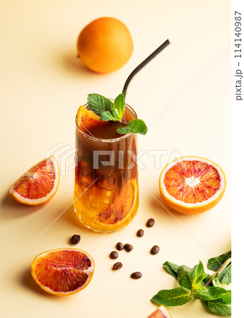 Espresso coffee with orange juice (bumble) in a tall glass with ice and mint on a yellow background 114140987