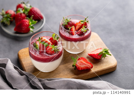 Strawberry and cream panna cotta in glasses with fresh berries on a wooden board  114140991