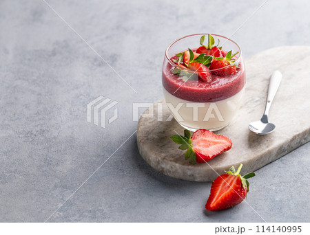 Strawberry and cream panna cotta in glass with fresh berries on a marble board on a light background 114140995
