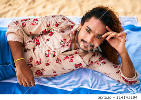 Relaxed gay man lounges on sandy beach, enjoying tropical sun. Casual floral shirt complements vibrant beach scene. Pride month vibes, holiday relaxation. Peaceful male sunbathing, pleasure seaside. Relaxed gay man lounges on sandy beach, enjoying tropical sun. Casual floral shirt complements vibrant beach scene. Pride month vibes, holiday relaxation. Peaceful male sunbathing, pleasure seaside. 114141194