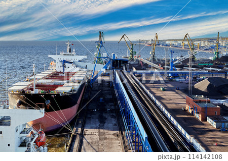 Coal harbor at maritime dry bulk terminal, bulk carrier under loading. Coal harbor at maritime dry bulk terminal, bulk carrier under loading. 114142108