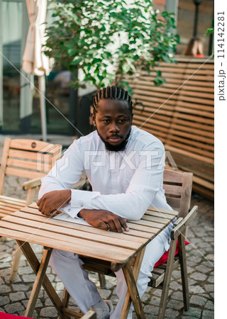 Cheerful male tourist portrait dress in white wear dashiki ethnic smiling at city street or small town background. African American travel model have free time. Millennial generation and gen z people 114142281