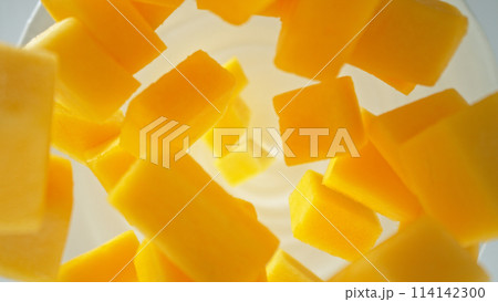 Fresh mango pieces falling into yoghurt cream, top down view 114142300
