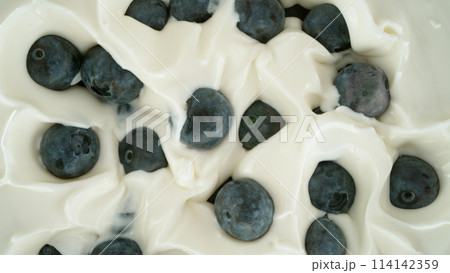 Fresh blueberries falling into yoghurt cream, top down view 114142359